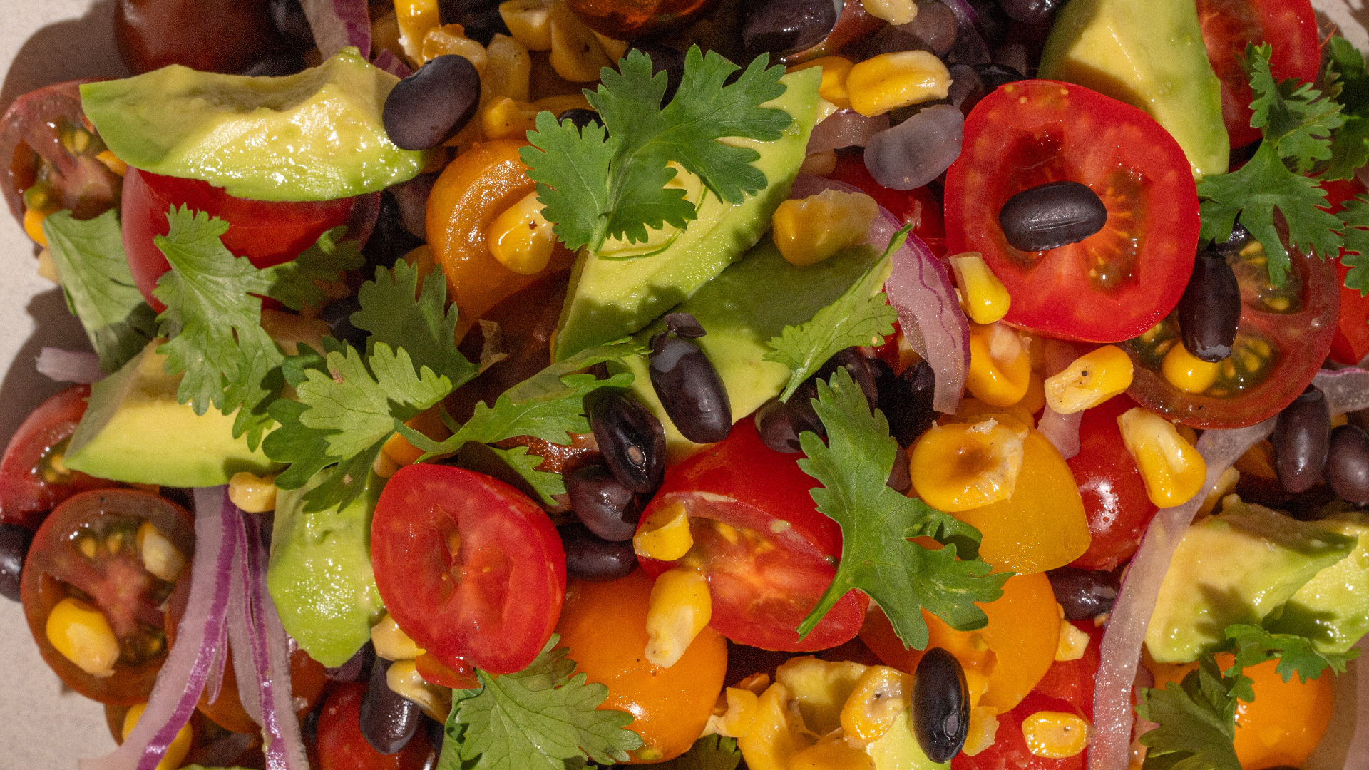 tomates cherry, maíz tostado, cebolla morada, porotos negros, palta y cilantro